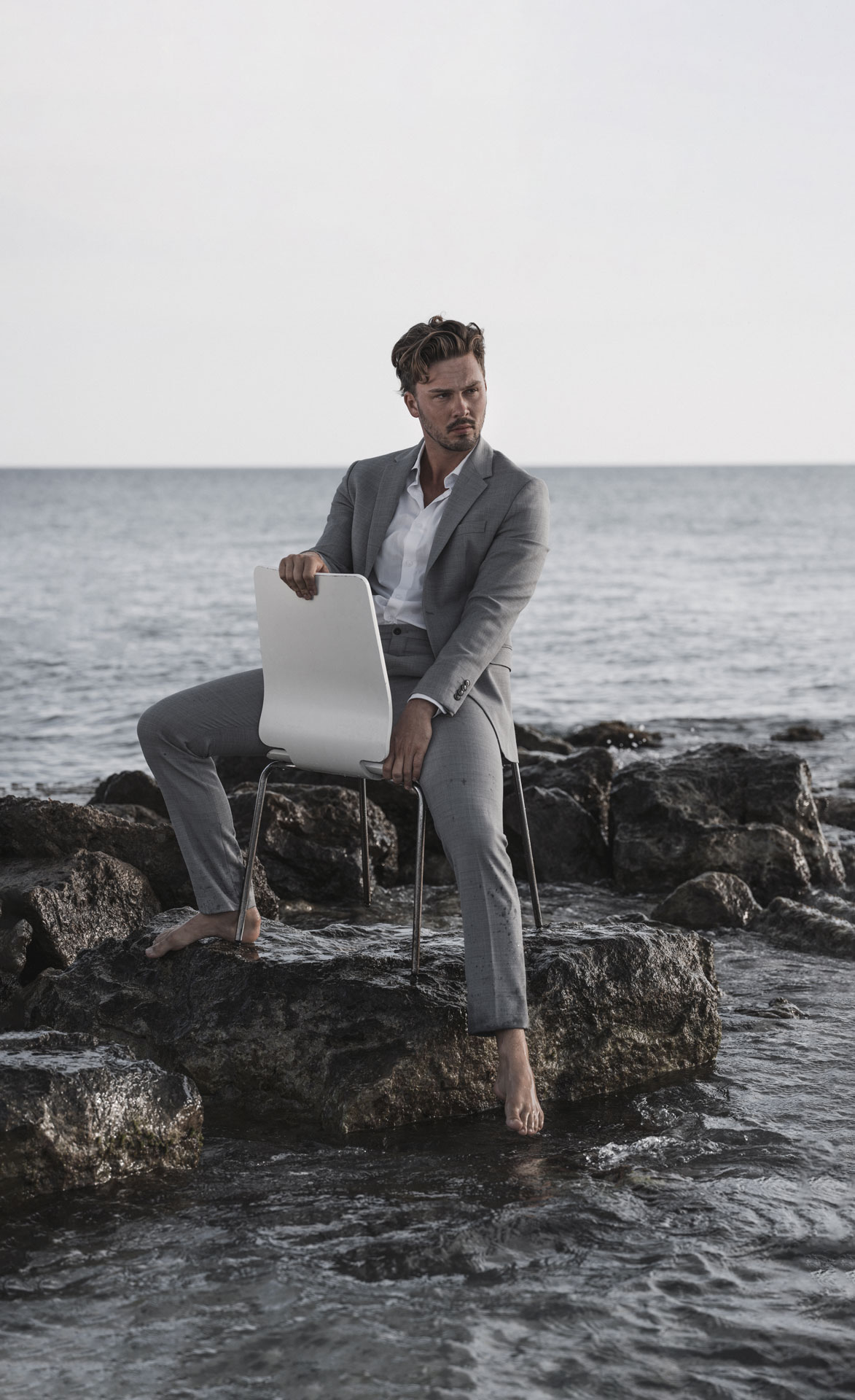 mann auf Stuhl im Wasser Fashion Shooting